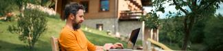 man on laptop outside cabin